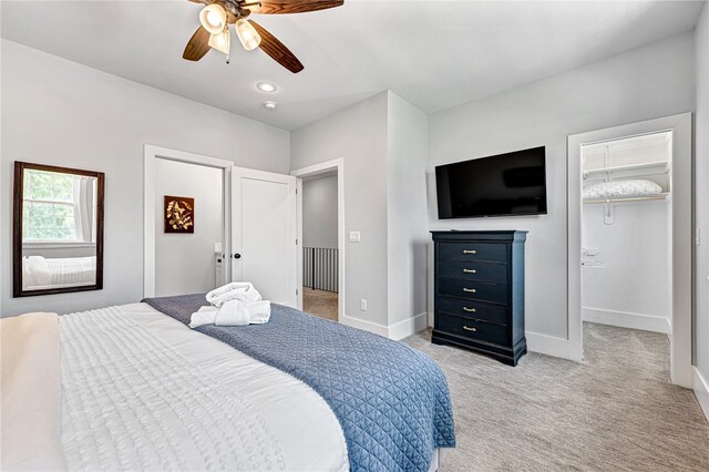 bedroom with ceiling fan, a walk in closet, light colored carpet, and a closet