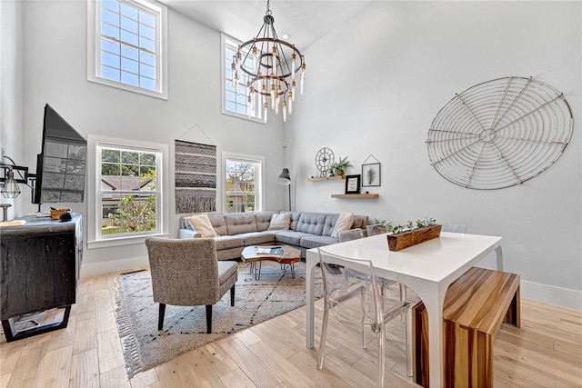 living room featuring a chandelier, a towering ceiling, and light wood-type flooring