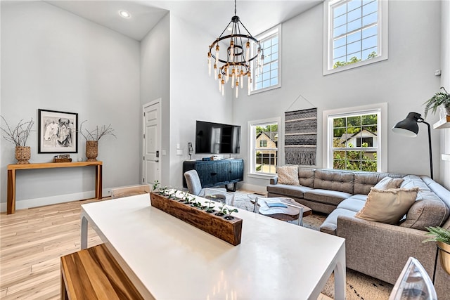 living room with a notable chandelier, a high ceiling, and light hardwood / wood-style floors