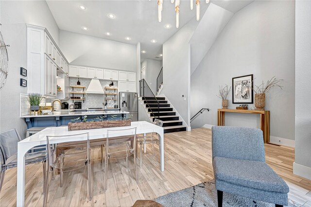 dining space with high vaulted ceiling, sink, and light wood-type flooring