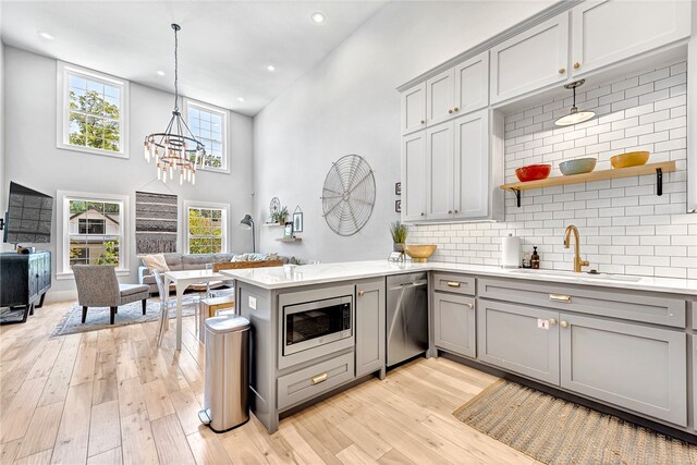 kitchen featuring stainless steel appliances, sink, a chandelier, and light hardwood / wood-style flooring