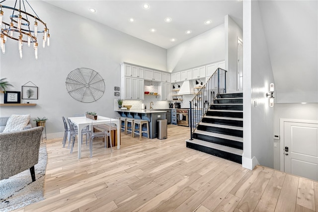 interior space featuring a notable chandelier, light hardwood / wood-style flooring, a towering ceiling, and sink