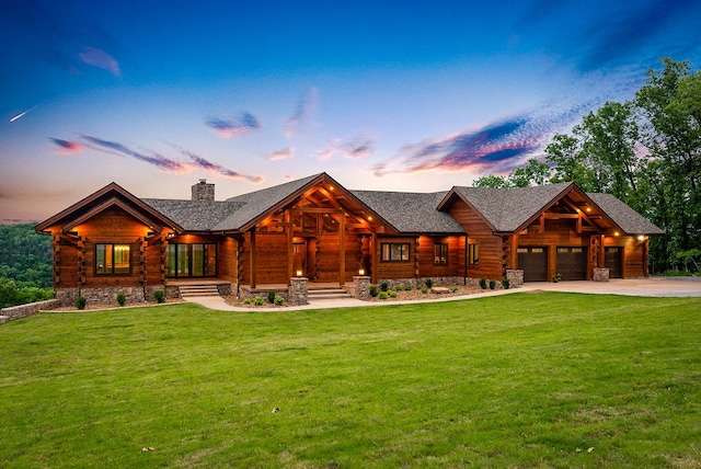 back house at dusk with a lawn and a garage