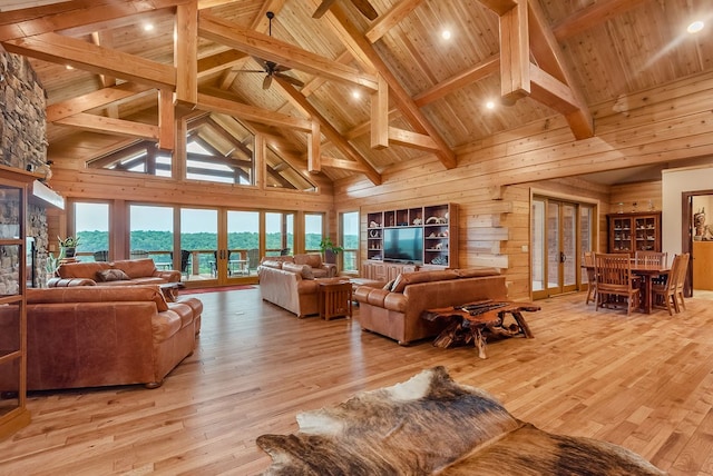 living room featuring wooden walls, high vaulted ceiling, light wood-type flooring, and a wealth of natural light