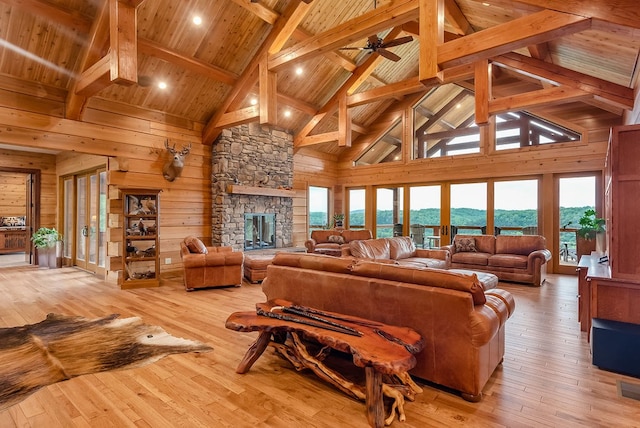 living room with a fireplace, wood walls, a healthy amount of sunlight, and light wood-type flooring