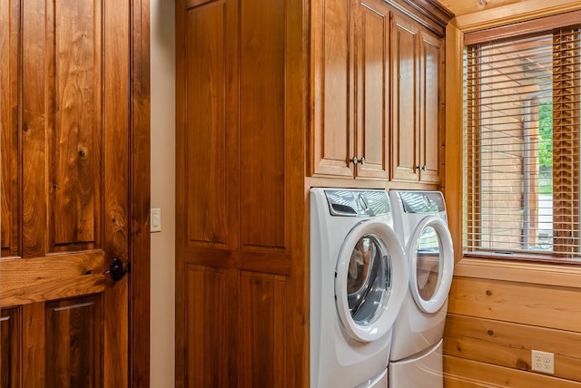 laundry room featuring washing machine and dryer, cabinets, and plenty of natural light