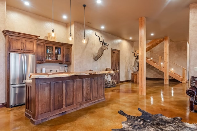 kitchen featuring a high ceiling, decorative light fixtures, stainless steel refrigerator, and light stone counters