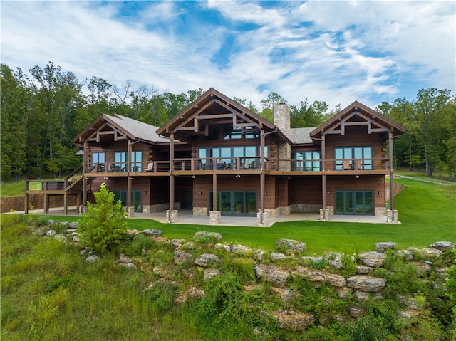 rear view of property featuring a balcony, a yard, and a patio area