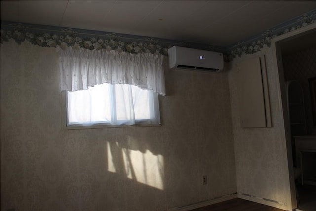 spare room featuring hardwood / wood-style flooring and a wall unit AC