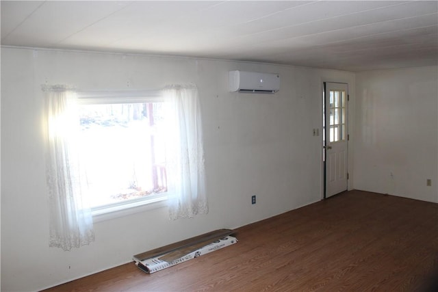 spare room featuring a healthy amount of sunlight, dark hardwood / wood-style flooring, and a wall mounted AC