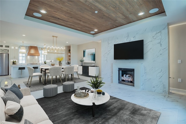 tiled living room with wooden ceiling, a high end fireplace, and a tray ceiling