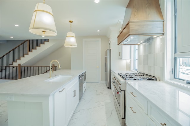 kitchen with premium appliances, hanging light fixtures, custom exhaust hood, sink, and a center island with sink