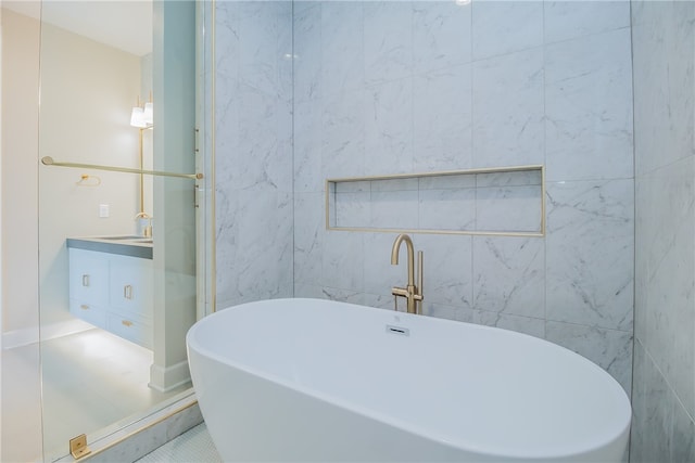 bathroom featuring vanity, tile flooring, a bathing tub, and tile walls