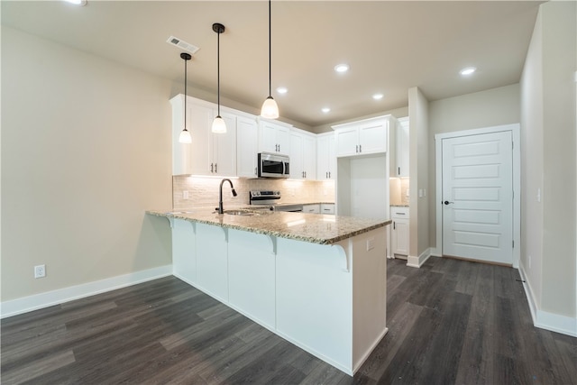 kitchen featuring white cabinetry, decorative light fixtures, dark wood-type flooring, and stainless steel appliances