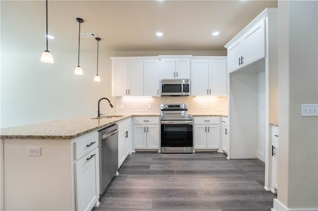 kitchen with appliances with stainless steel finishes, sink, white cabinetry, pendant lighting, and dark wood-type flooring