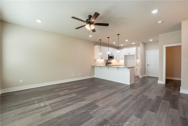 kitchen with kitchen peninsula, decorative light fixtures, white cabinets, light stone counters, and dark hardwood / wood-style floors