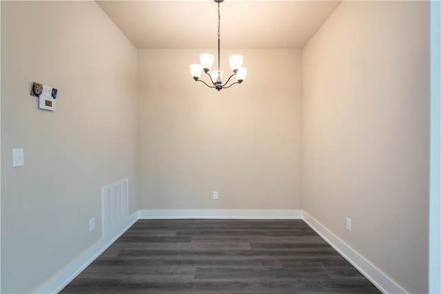 unfurnished dining area featuring an inviting chandelier and dark hardwood / wood-style flooring