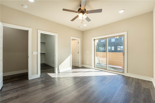 unfurnished bedroom with a closet, ceiling fan, dark hardwood / wood-style flooring, and a walk in closet