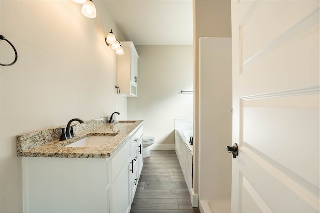 bathroom featuring vanity, toilet, hardwood / wood-style flooring, and a washtub