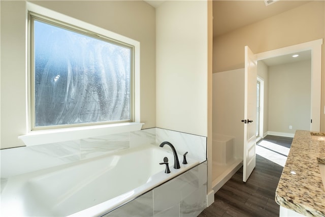 bathroom with vanity, hardwood / wood-style floors, and a tub to relax in