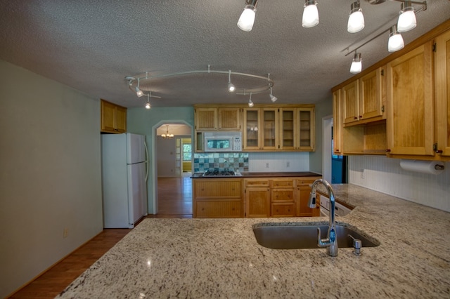 kitchen with sink, white appliances, track lighting, and a textured ceiling