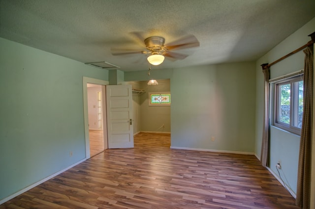 empty room featuring dark hardwood / wood-style flooring, ceiling fan, and a textured ceiling