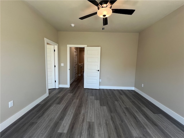 unfurnished bedroom featuring ceiling fan, a closet, dark wood-type flooring, and a spacious closet