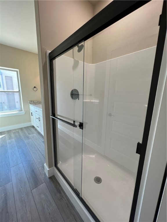 bathroom featuring an enclosed shower, vanity, and wood-type flooring