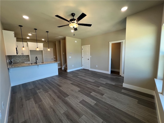 kitchen featuring white cabinetry, dark hardwood / wood-style floors, ceiling fan, light stone counters, and tasteful backsplash