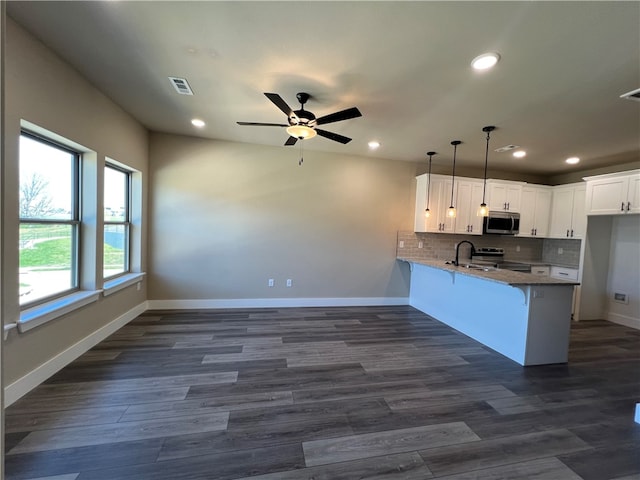 kitchen featuring decorative light fixtures, white cabinetry, ceiling fan, stainless steel appliances, and tasteful backsplash