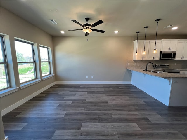 kitchen with appliances with stainless steel finishes, ceiling fan, backsplash, kitchen peninsula, and white cabinets