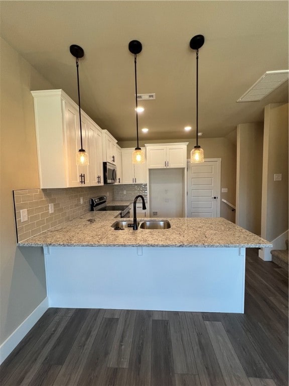 kitchen with white cabinetry, dark hardwood / wood-style floors, appliances with stainless steel finishes, sink, and pendant lighting