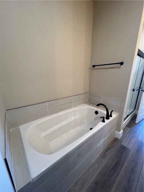 bathroom with plus walk in shower and hardwood / wood-style flooring