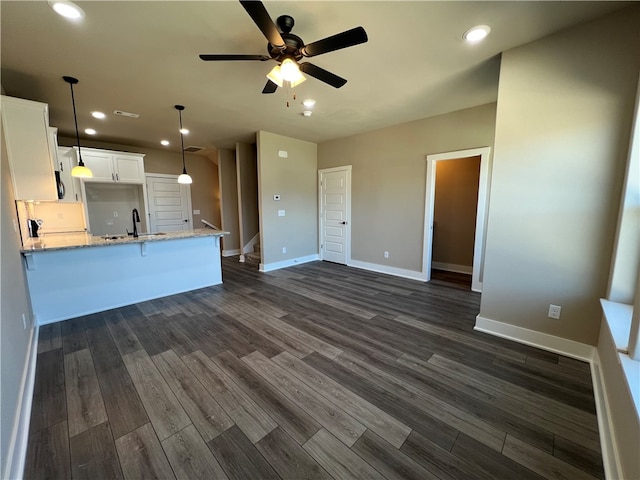 kitchen with pendant lighting, ceiling fan, dark hardwood / wood-style flooring, light stone countertops, and white cabinets