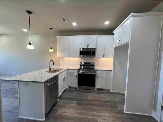 kitchen featuring pendant lighting, stainless steel appliances, sink, white cabinetry, and light stone countertops