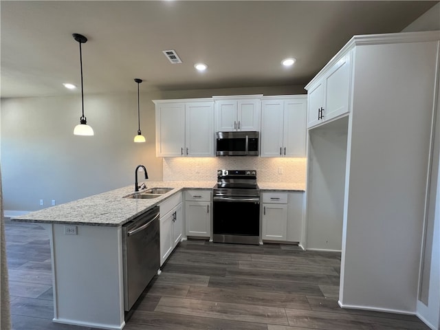 kitchen with kitchen peninsula, appliances with stainless steel finishes, white cabinets, hanging light fixtures, and sink