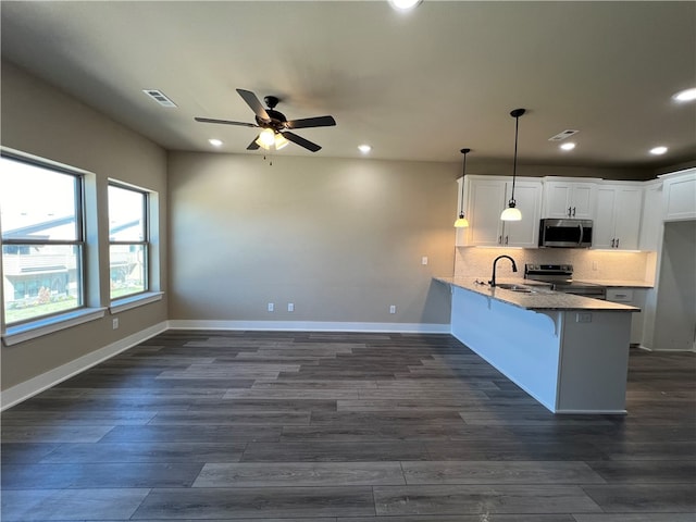 kitchen featuring pendant lighting, ceiling fan, tasteful backsplash, appliances with stainless steel finishes, and white cabinetry