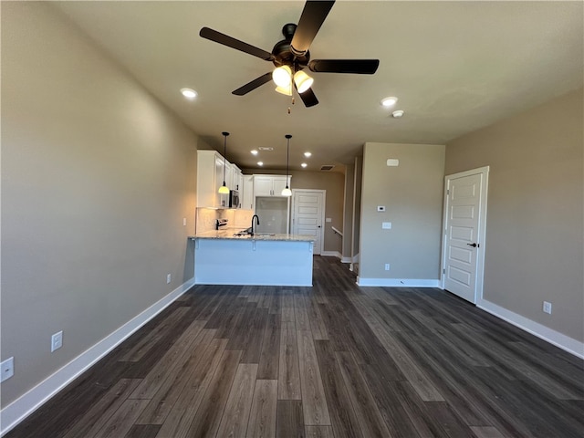 unfurnished living room with ceiling fan, sink, and dark wood-type flooring