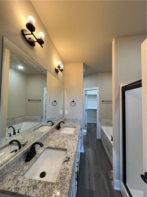 bathroom with wood-type flooring, double sink, oversized vanity, and a tub