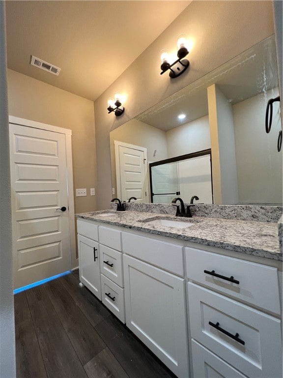 bathroom with dual bowl vanity and wood-type flooring