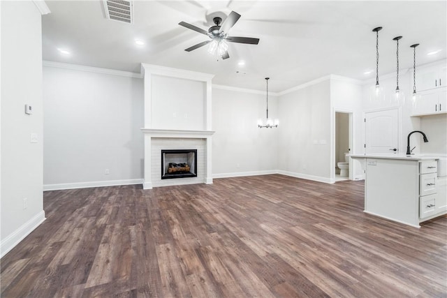 unfurnished living room featuring dark wood-type flooring, ceiling fan, crown molding, and sink