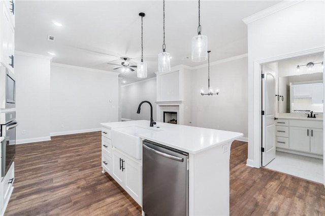 kitchen with white cabinets, ceiling fan with notable chandelier, hanging light fixtures, a kitchen island with sink, and appliances with stainless steel finishes