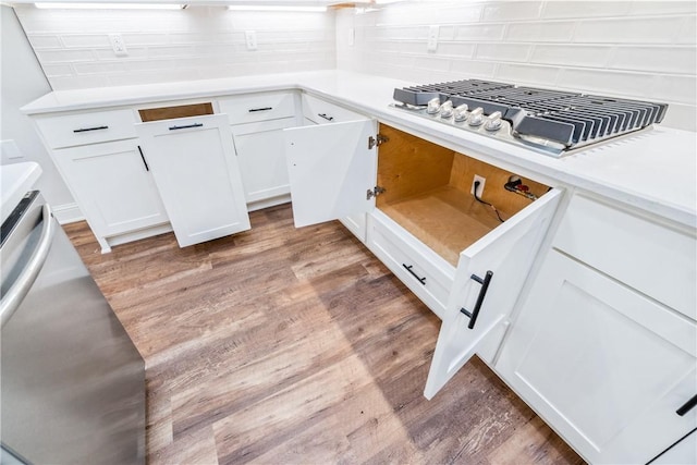 kitchen with light hardwood / wood-style floors, white cabinetry, backsplash, and stainless steel gas cooktop