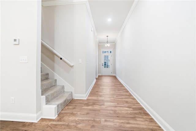 hallway with ornamental molding and light hardwood / wood-style flooring