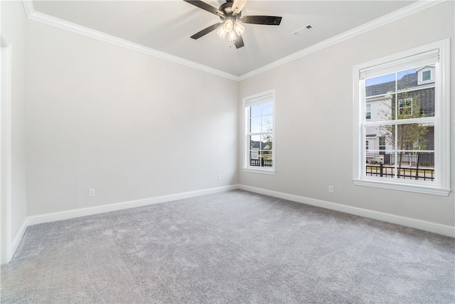 carpeted spare room with ceiling fan, ornamental molding, and a wealth of natural light