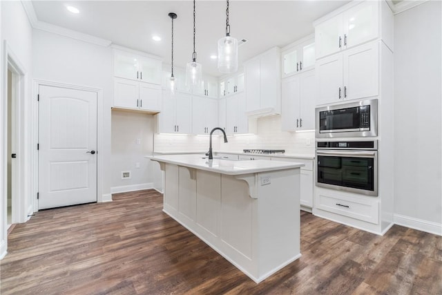 kitchen featuring oven, white cabinetry, a center island with sink, and built in microwave