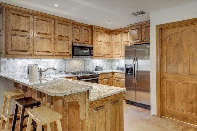 kitchen featuring kitchen peninsula, a breakfast bar area, stainless steel appliances, light stone countertops, and tasteful backsplash