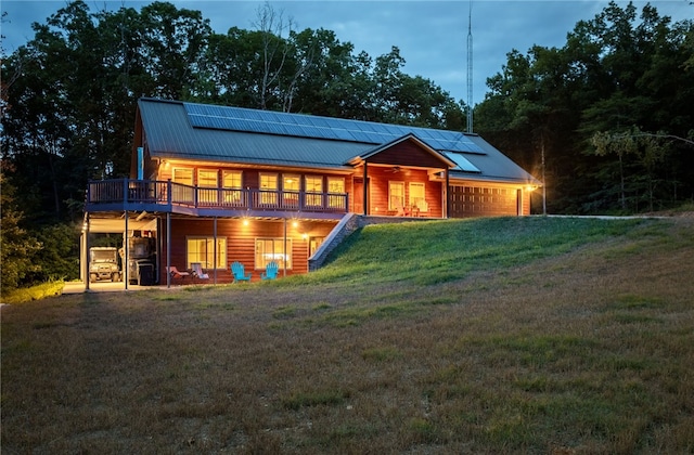 view of front of home with a balcony, solar panels, and a lawn