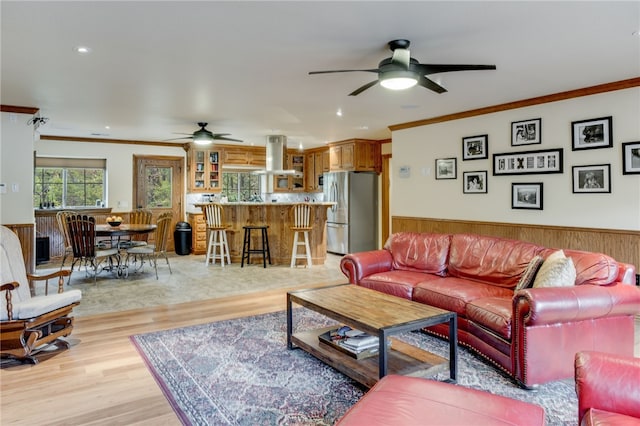 living room featuring ceiling fan, light wood-type flooring, and ornamental molding