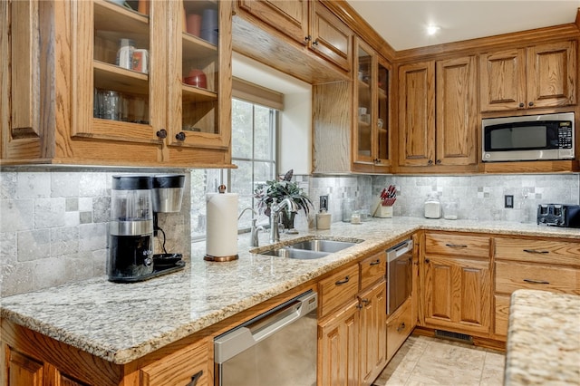 kitchen featuring light tile floors, appliances with stainless steel finishes, backsplash, and light stone countertops